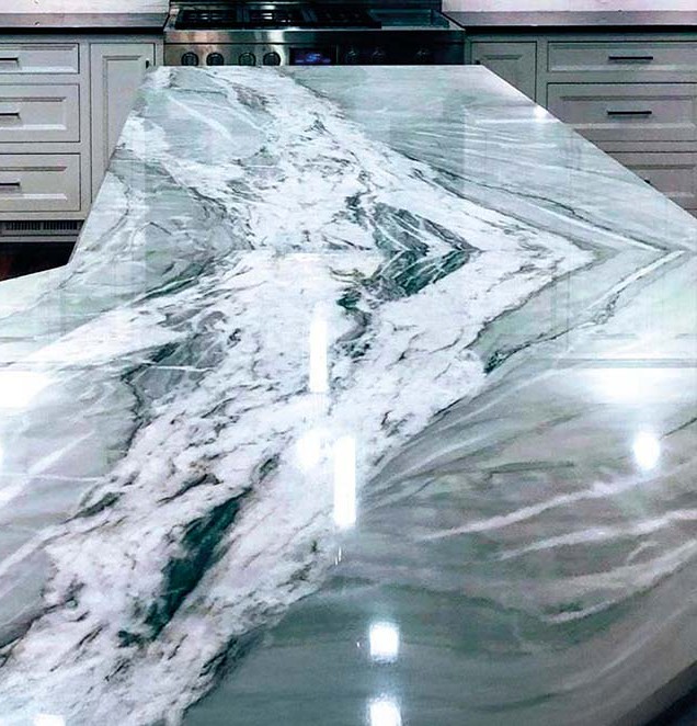 Mesada de cocina color gris con distintas tonalidades de gris y blanco, atrás muebles de color blanco