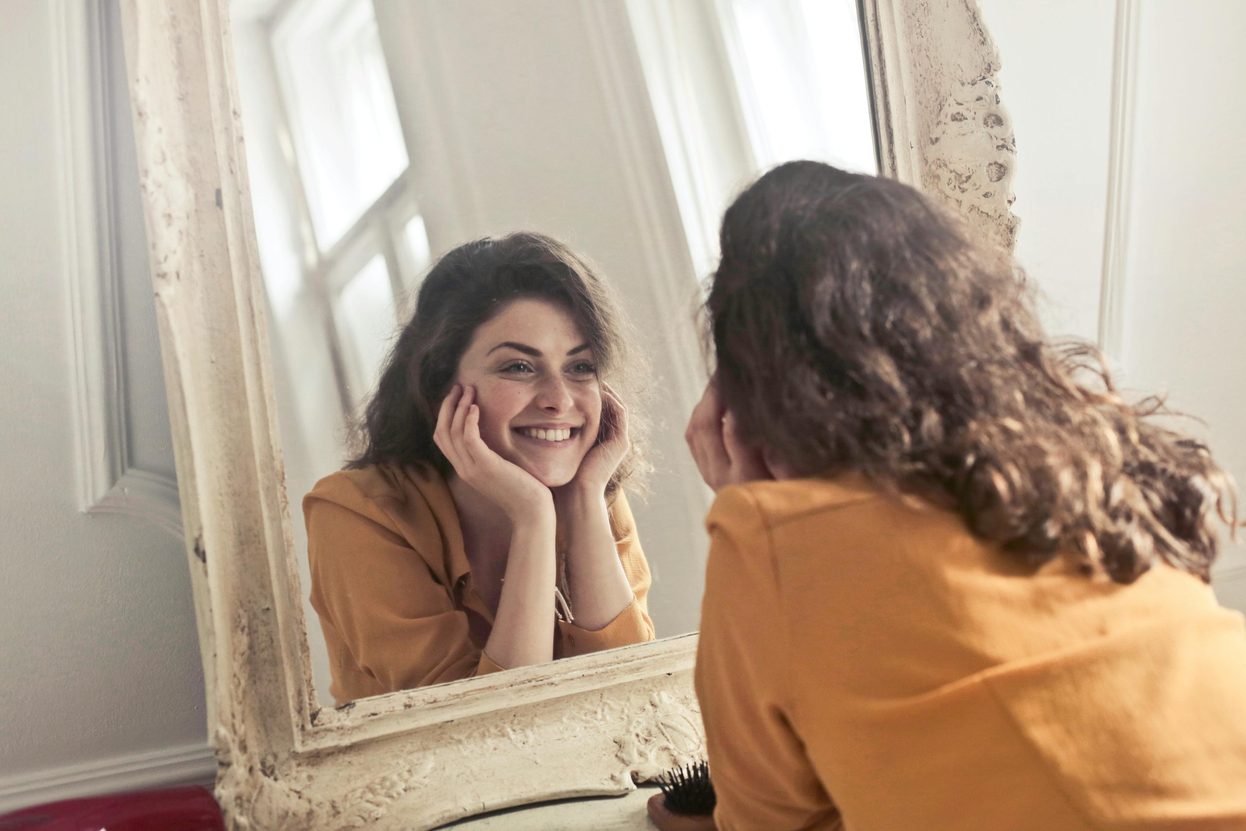 persona sonriendo al espejo, habito que refuerza el autoestima