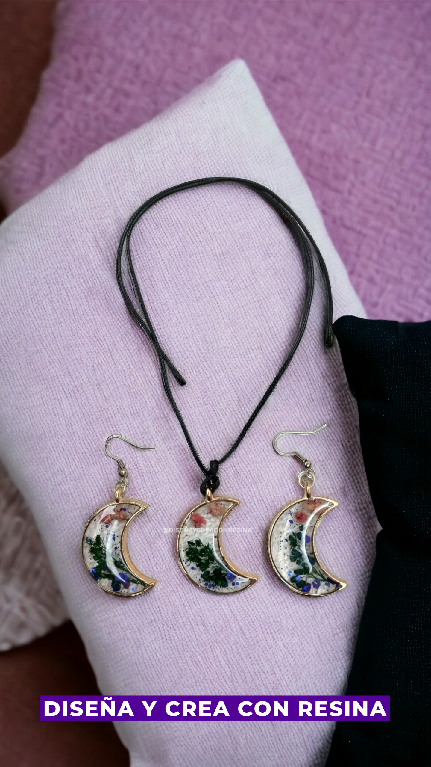 collar y pendientes transparentes con fomra de media luna en el centro una plantas verdes y flores azul y rosadas 