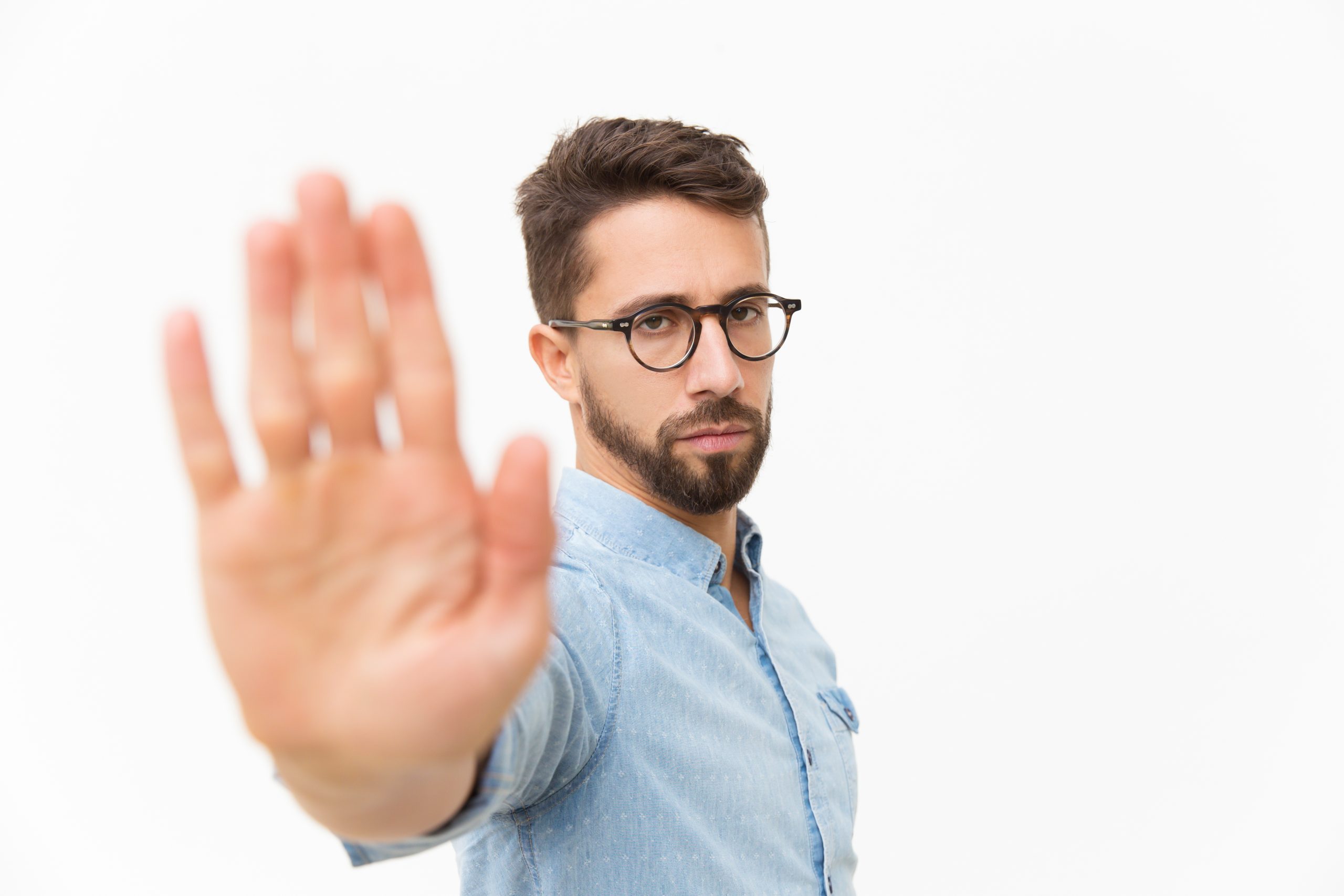 masculino de rostro serio poniendo una mano como diciendo "pare" poniendo un límite