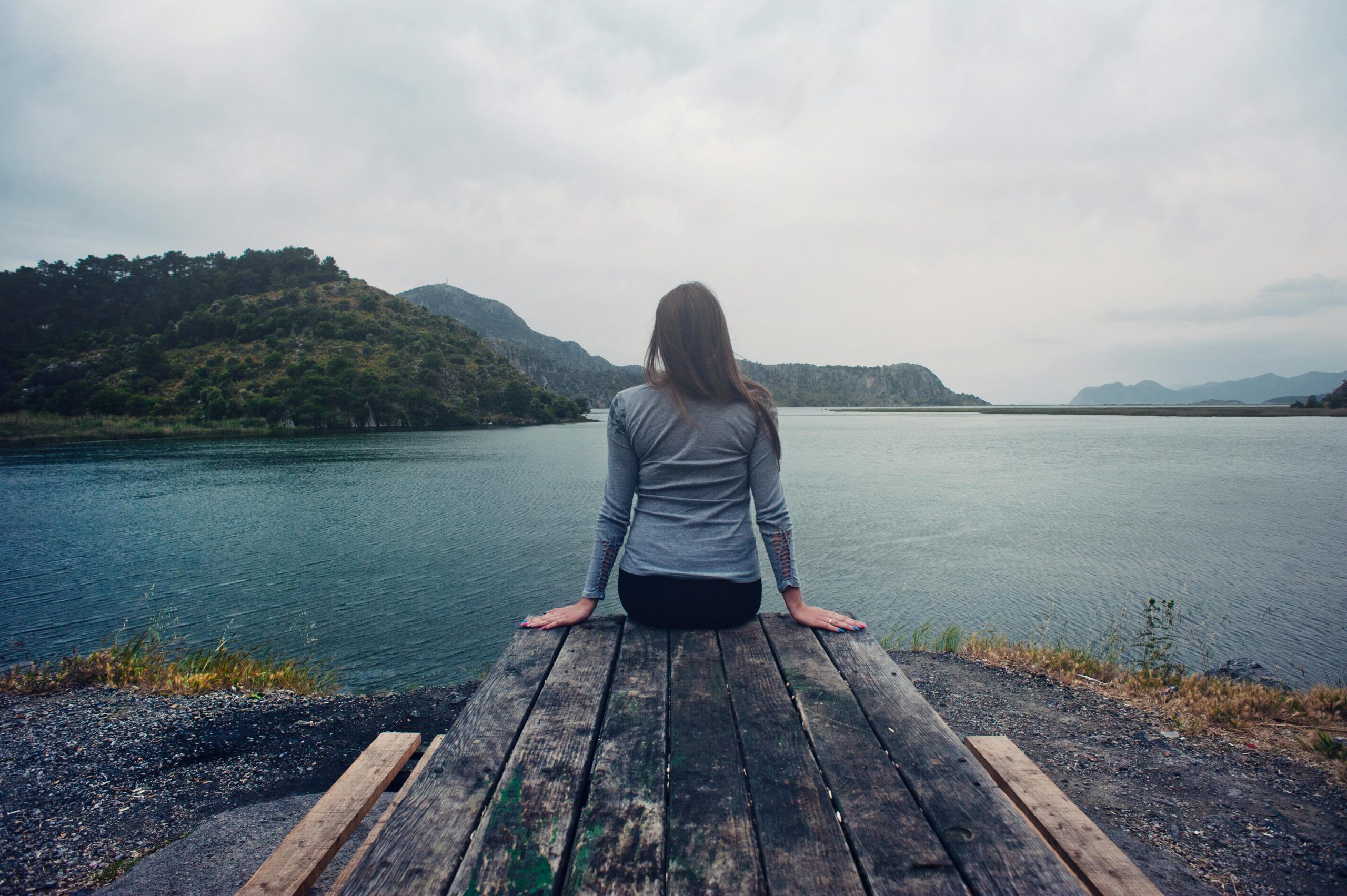 persona sentada sobre mesa al borde de un lago cuidando su salud mental